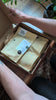 Hands unboxing the Revelation Pack, opening a kraft box to reveal three award-winning Indian coffee bags inside